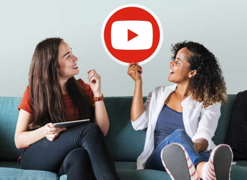 Two women viewing the YouTube logo