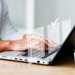 Man's hands on laptop keyboard with virtual documents