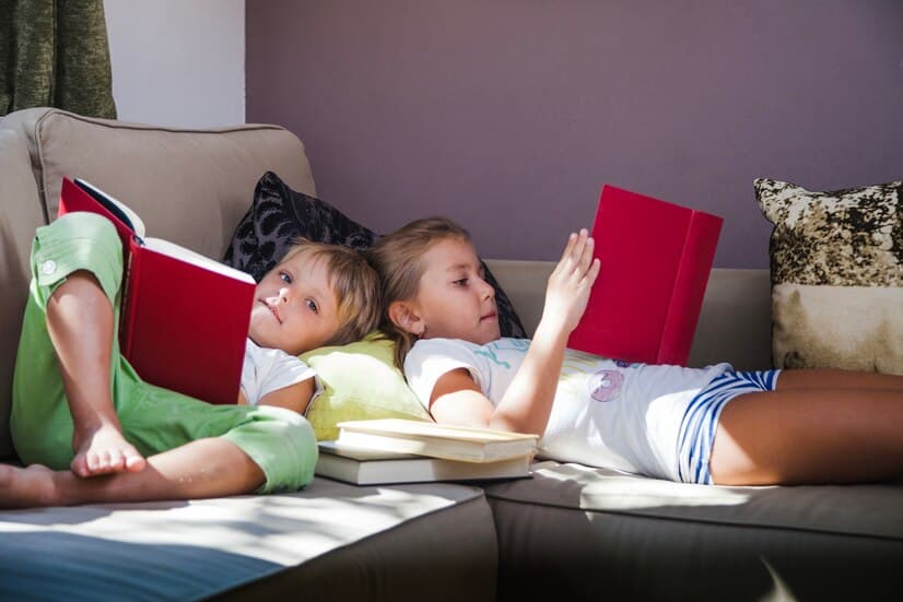 Kids are Lying on the Couch With Books in Hands
